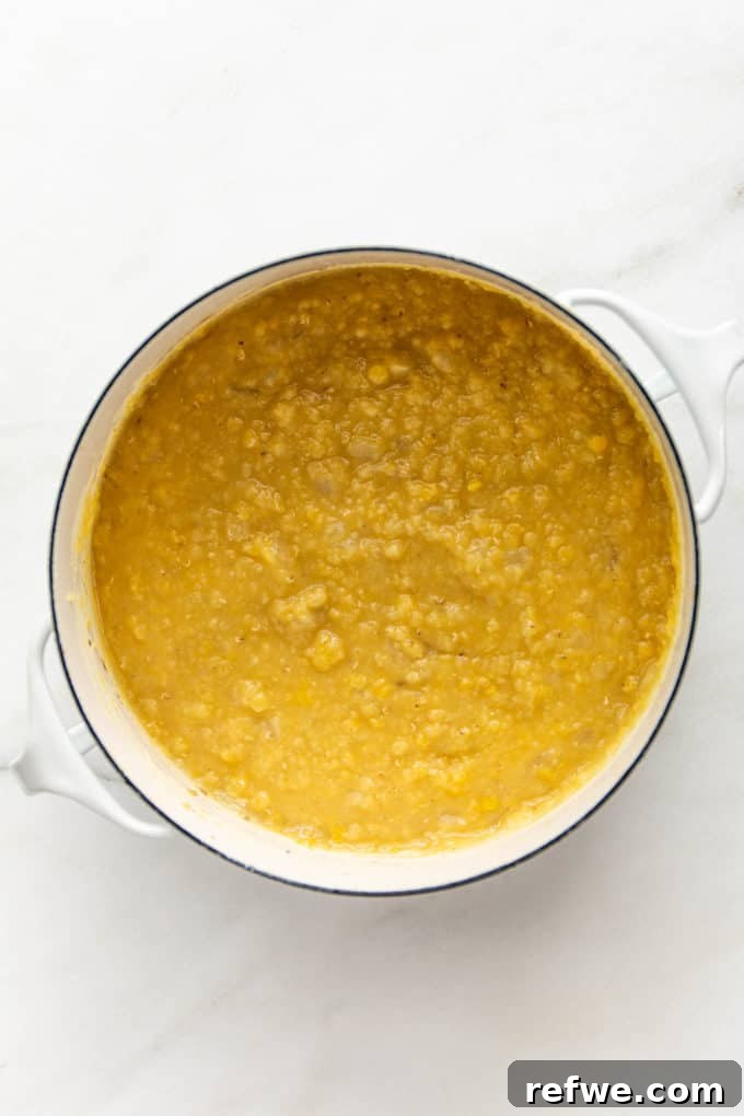 A white pot filled with perfectly cooked, creamy red lentils, ready for the next step.