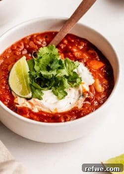 vegan chili topped with cilantro and lime in a white bowl