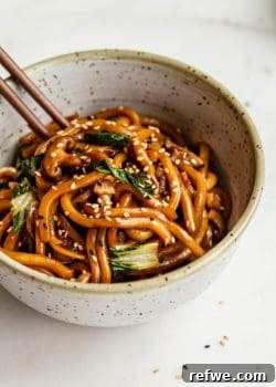 Yaki udon in a speckled ceramic bowl with wood chopsticks in it