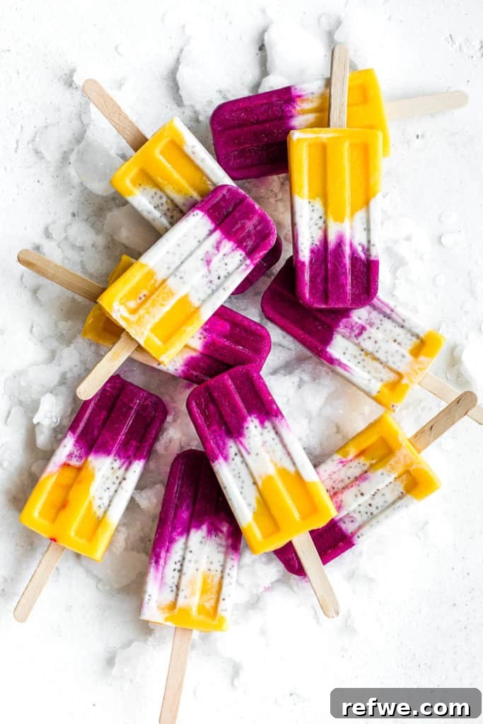 Exotic Coconut Chia Chillers 2 Stacked tropical coconut chia popsicles with vibrant layers of mango, coconut, and dragonfruit, artfully arranged on a rustic board with ice, evoking a refreshing summer vibe.