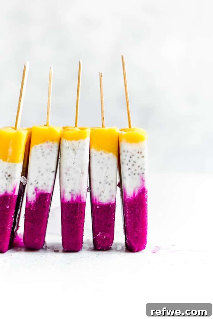 Exotic Coconut Chia Chillers 5 Five tropical coconut chia popsicles, beautifully layered with mango, coconut, and dragonfruit, neatly stacked side by side on a clean white surface, highlighting their vibrant colors.