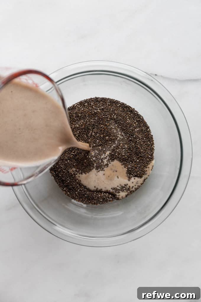 Festive Eggnog Chia Pudding 5 a measuring cup pouring eggnog into a bowl of chia seeds, illustrating the combination