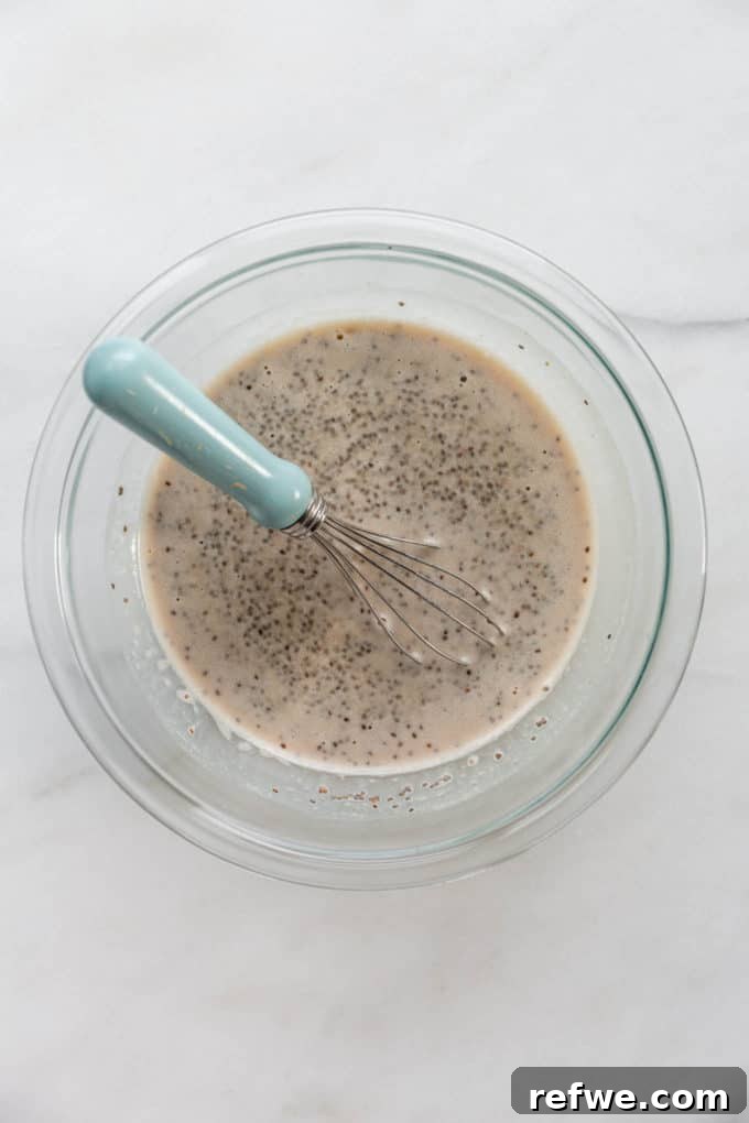 Festive Eggnog Chia Pudding 6 eggnog and chia seeds in a mixing bowl with a whisk, showing the blending process
