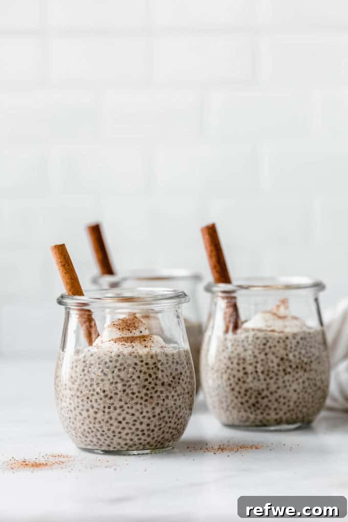 Festive Eggnog Chia Pudding 8 Eggnog chia pudding in a jar topped with yogurt and a cinnamon stick, ready to be eaten