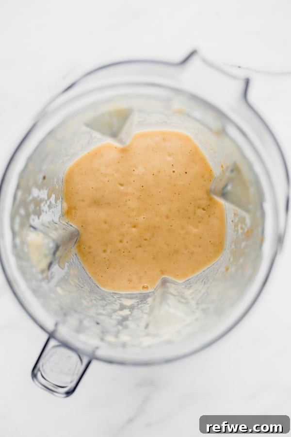 A high-angle shot of a blender filled with a freshly prepared, creamy papaya mojito smoothie, ready to be poured into glasses.