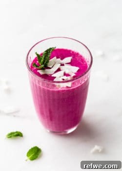 A dragon fruit smoothie in a glass topped with coconut flakes, featured in the recipe card.