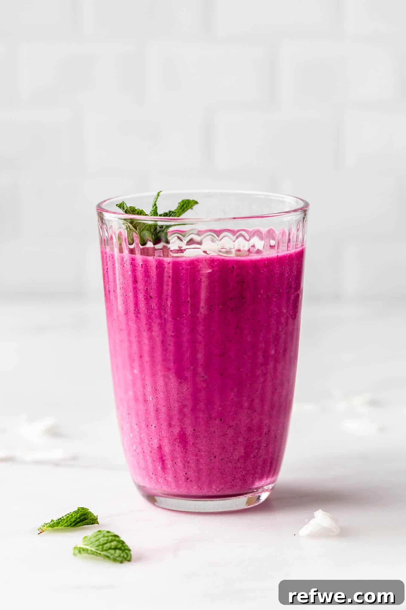 Pitaya Paradise Smoothie 7 A glass of vibrant dragon fruit smoothie sitting on a light marble counter, bathed in natural light, ready to be enjoyed.