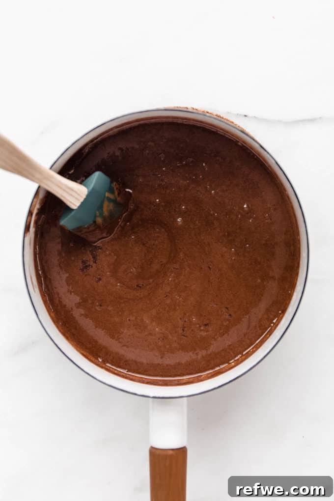 Chocolate Coconut No Bake Dream Bars 4 Melted chocolate, coconut oil, and almond butter blend smoothly in a white pot, creating a rich base for the bars.