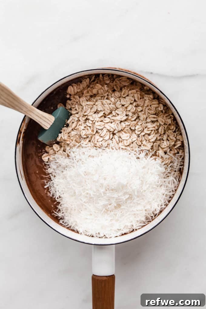 Chocolate Coconut No Bake Dream Bars 5 The vibrant mixture of chocolate, oats, and shredded coconut waits in a white pot, ready for the next step.