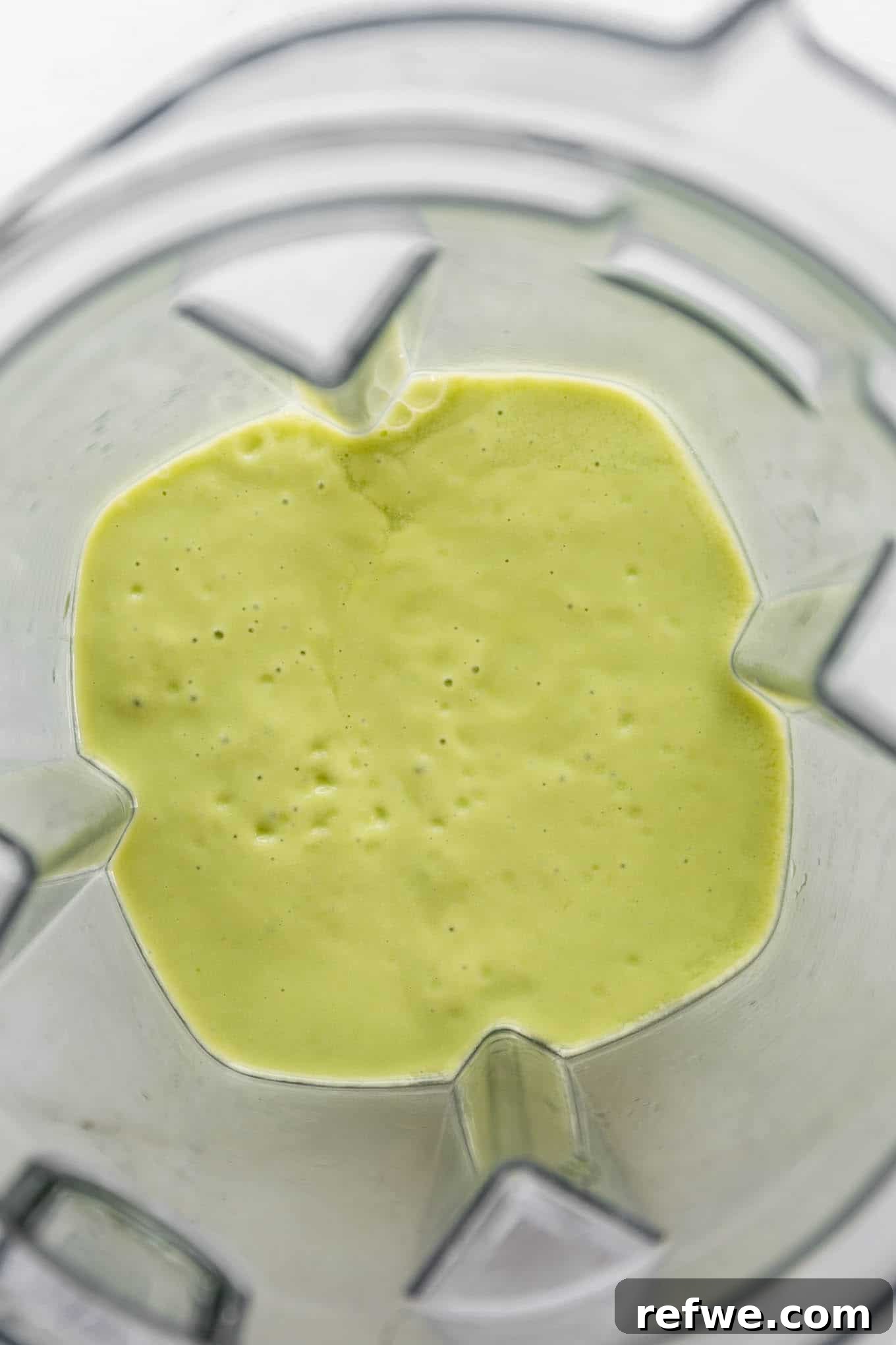 Tropical Green Dream 5 The mango avocado smoothie actively blending in a high-speed blender, creating a smooth, creamy texture.