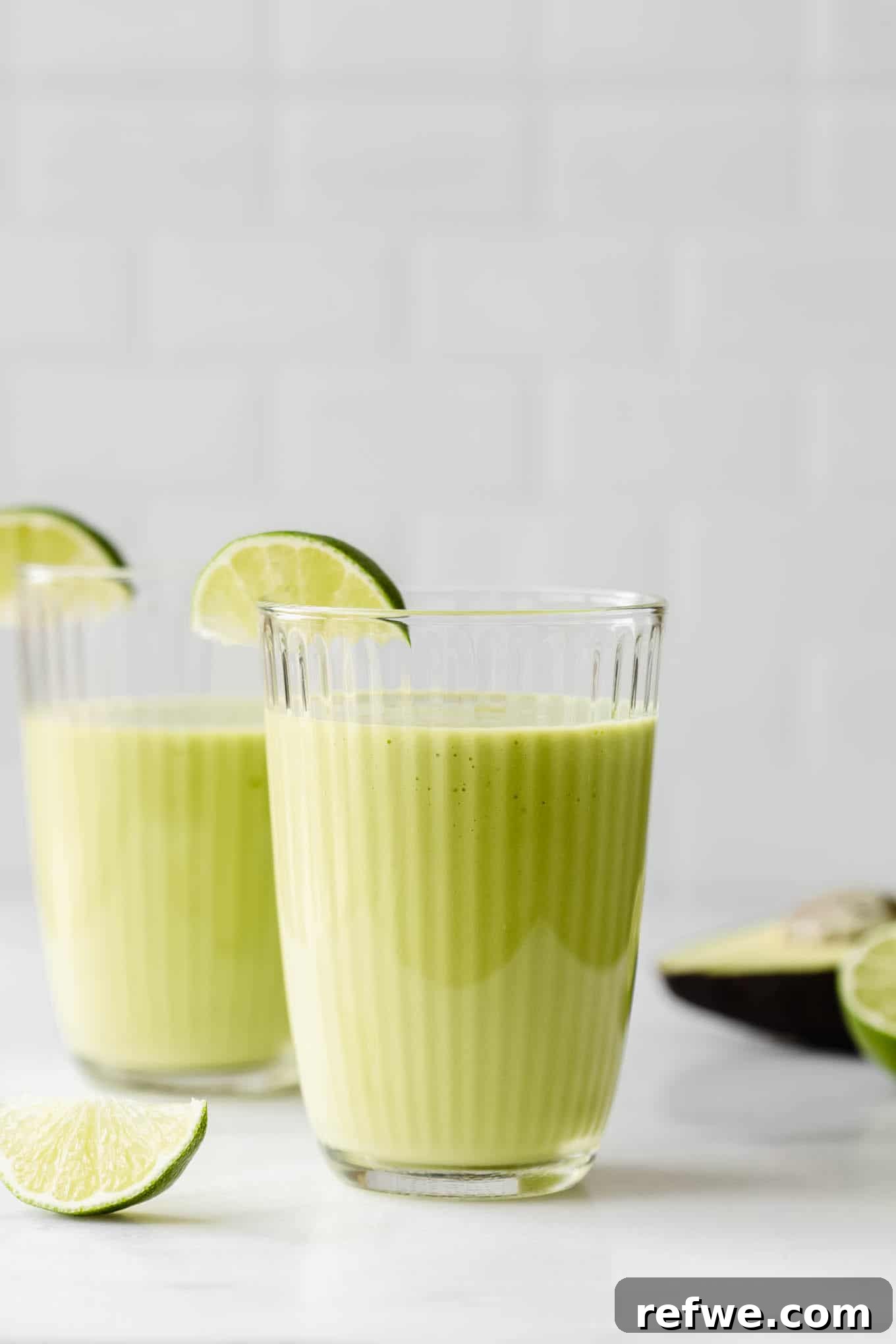 Tropical Green Dream 6 Two perfectly blended avocado mango smoothies poured into elegant glasses, ready to be served and enjoyed on a clean counter.