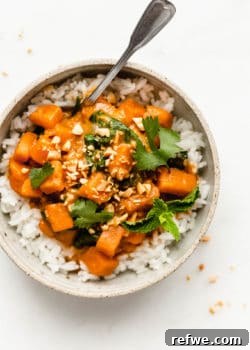 a bowl of sweet potato curry on rice topped with cilantro and mint