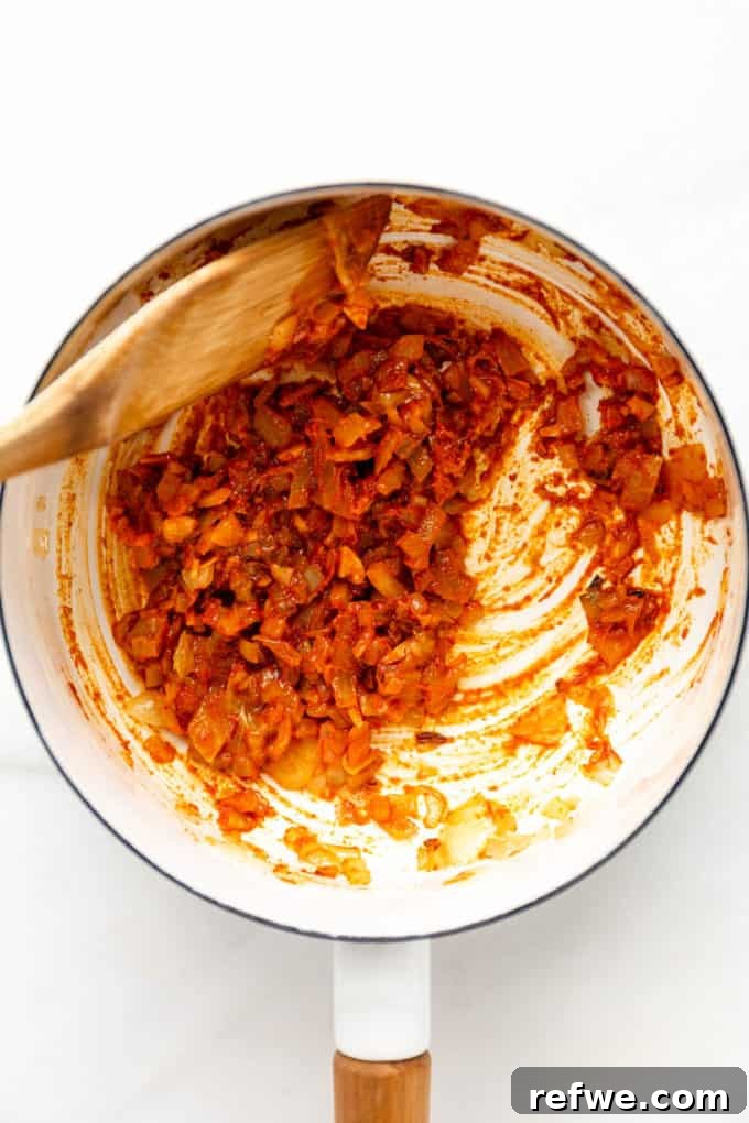 A close-up view of the sautéed curry paste and onions, deeply fragrant and ready for the next step in a white pot