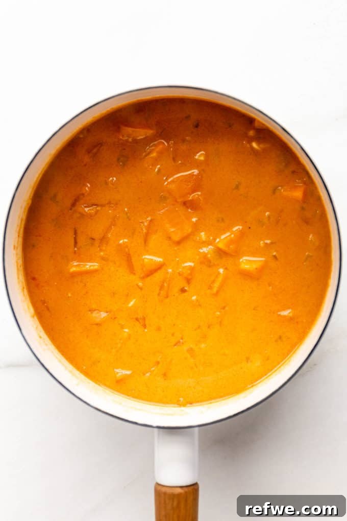 The fully cooked sweet potato curry, rich and creamy, with tender sweet potatoes, bubbling gently in a white pot