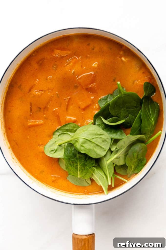 The rich, cooked sweet potato curry, now infused with vibrant fresh spinach, ready to be served from the pot