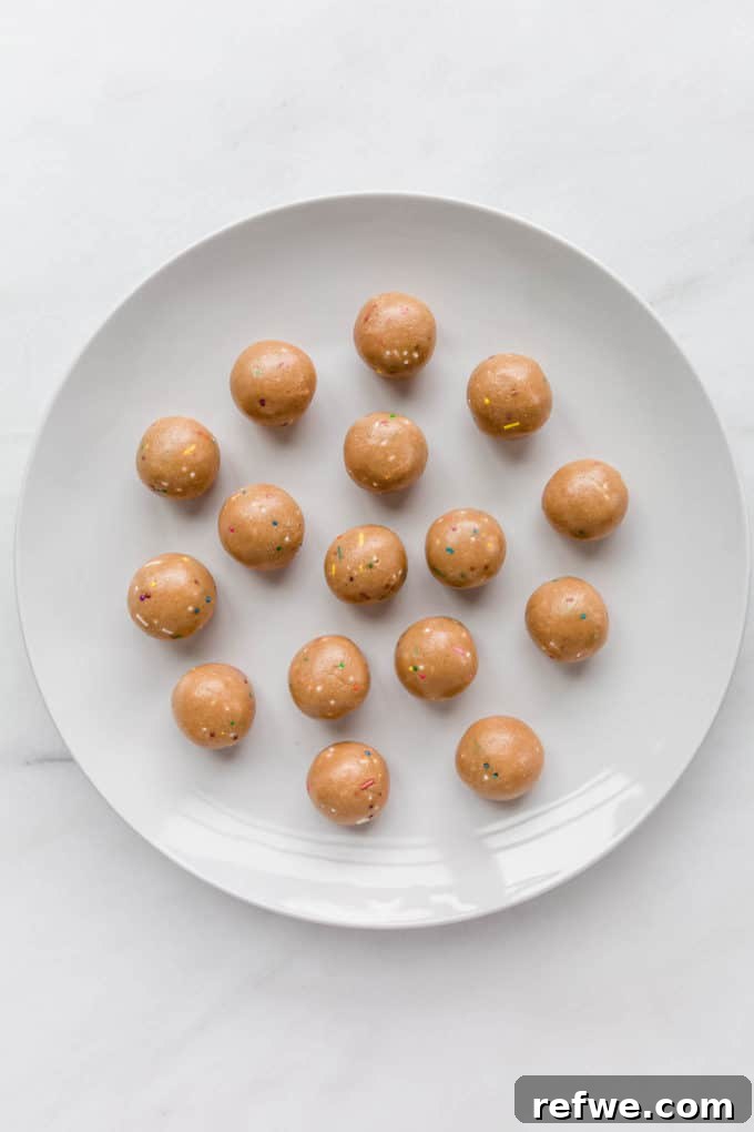 Funfetti Protein Bites 11 A collection of colorful Birthday Cake Protein Balls arranged neatly on a pristine white plate, freshly chilled.