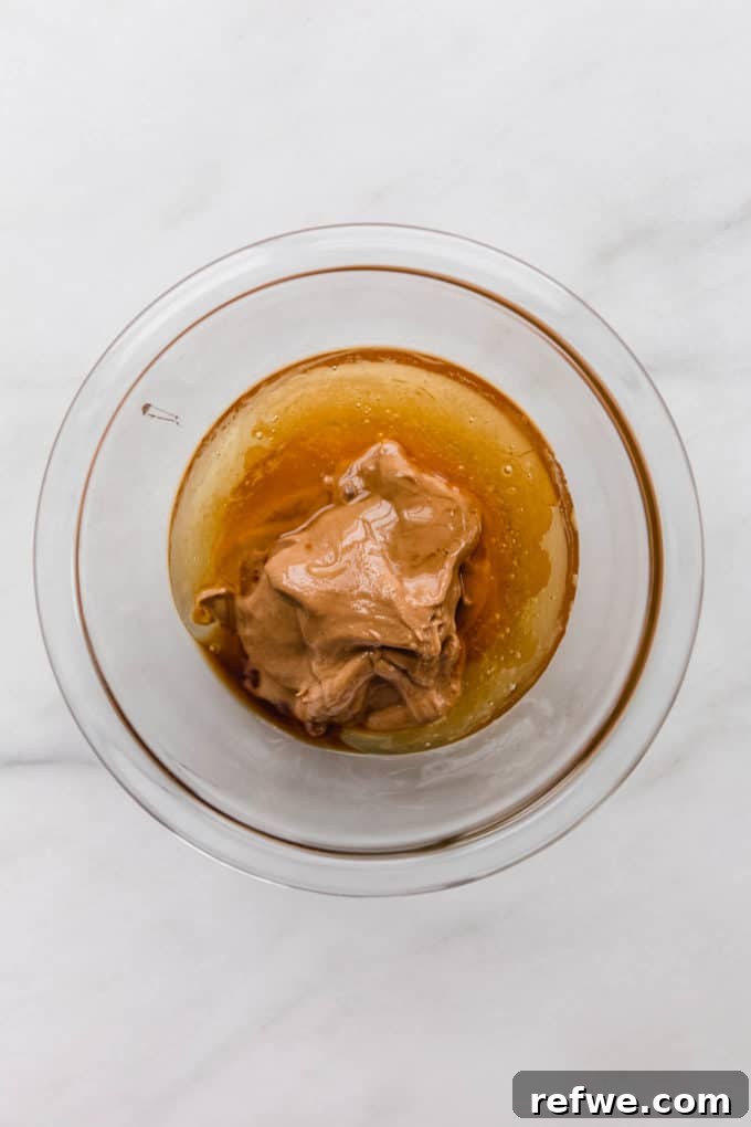 Funfetti Protein Bites 3 Creamy honey and rich cashew butter expertly mixed in a clear bowl, creating a smooth wet base.