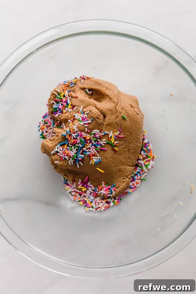 Funfetti Protein Bites 8 Festive, colorful sprinkles being carefully mixed into the protein ball dough in a mixing bowl, adding a pop of color and fun.