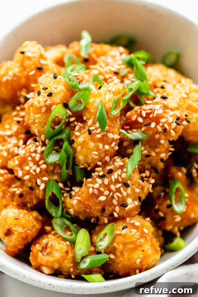 Sunkissed Cauliflower 2 Crispy baked orange cauliflower topped with fresh sesame seeds and vibrant green scallions, ready to be served.