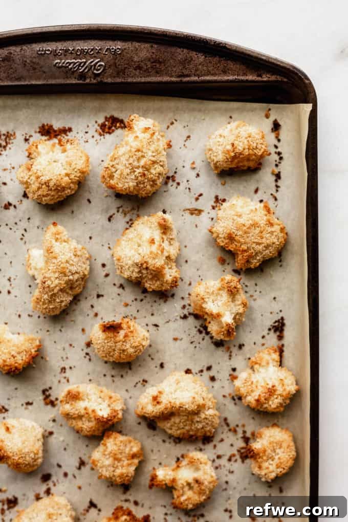 Sunkissed Cauliflower 7 Perfectly baked panko-crusted cauliflower florets, golden brown and crispy, resting on a parchment-lined baking sheet after cooking.