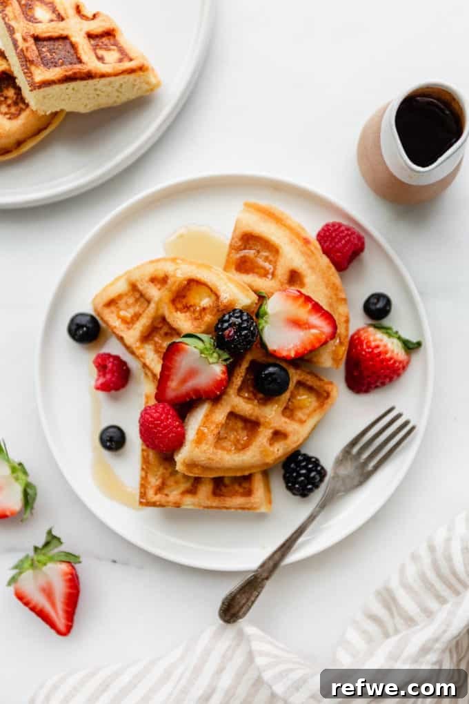 Fluffy Almond Flour Waffles 2 A plate of fluffy almond flour waffles generously topped with vibrant strawberries, juicy blackberries, fresh blueberries, and sweet raspberries.