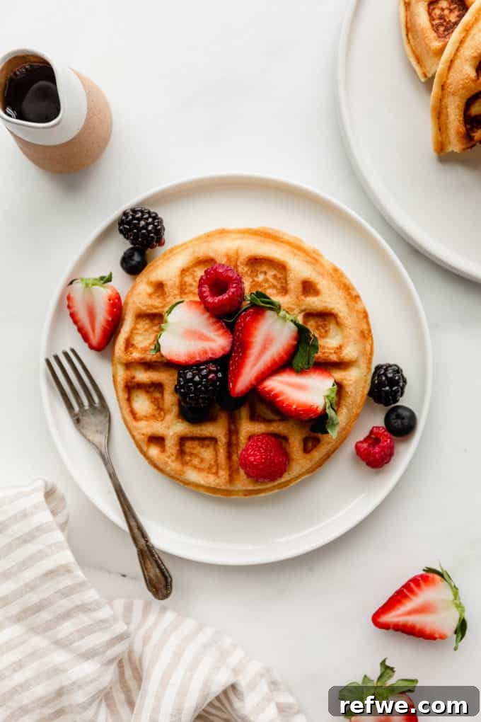 Fluffy Almond Flour Waffles 11 A delicious almond flour waffle, artfully topped with an assortment of fresh berries, resting on a pristine white plate.