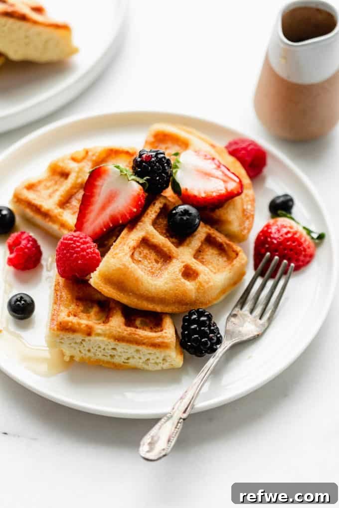 Fluffy Almond Flour Waffles 12 A beautifully presented plate of almond flour waffles, generously garnished with a colorful assortment of fresh berries, ready to be enjoyed.