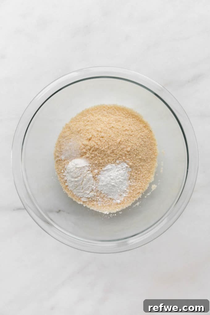 Fluffy Almond Flour Waffles 4 A clear mixing bowl filled with dry ingredients: almond flour, baking powder, tapioca starch, and salt, perfectly combined.
