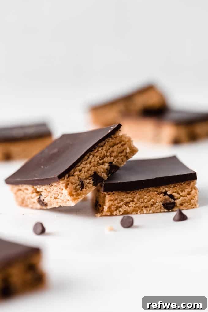 Fırınsız Sağlıklı Kurabiye Hamuru Barları 12 Two healthy no-bake cookie dough bars, perfectly portioned and ready to enjoy, surrounded by scattered chocolate chips.
