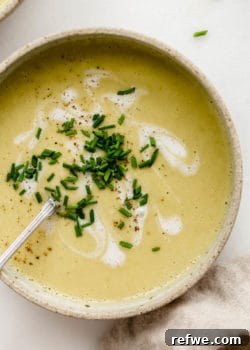Vegan Broccoli Soup with chives on top in a white bowl.