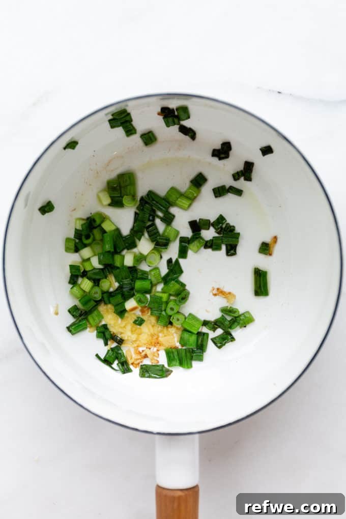 Whip Up Miso Ramen in 15 Minutes 5 Chopped scallions and grated ginger sizzling in avocado oil in a white pot, building the aromatic base for miso ramen.
