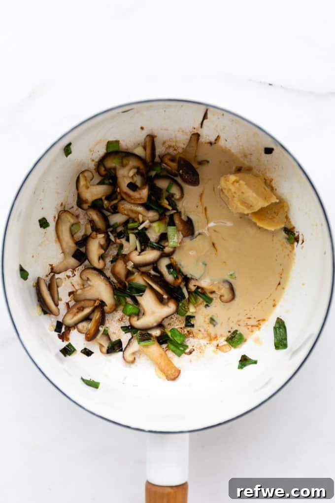 Whip Up Miso Ramen in 15 Minutes 7 Sautéed shiitake mushrooms, scallions, and ginger mixed with miso paste and tahini in a white pot, ready for the broth.