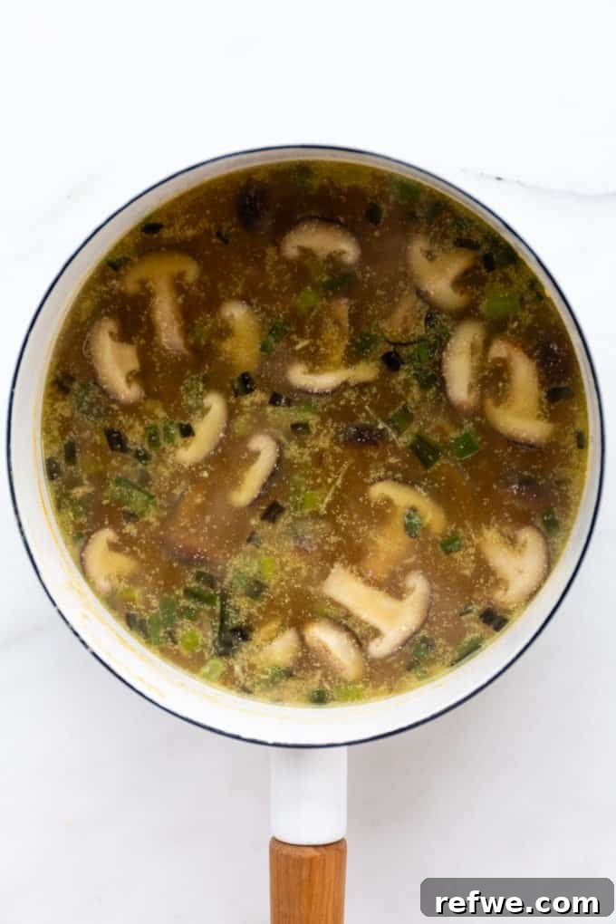 Whip Up Miso Ramen in 15 Minutes 9 Miso ramen soup simmering in a white pot, filled with aromatic broth and shiitake mushrooms.
