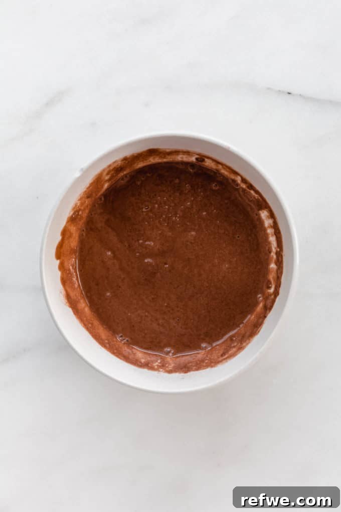 Decadent Tiramisu Chia Pudding 3 Cocoa powder, chia seeds, and coconut milk being mixed in a bowl for the chocolate layer.