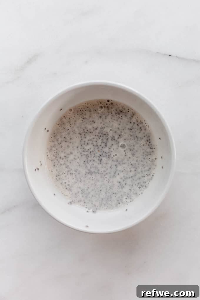 Decadent Tiramisu Chia Pudding 7 Coconut milk and chia seeds in a white bowl, ready to be mixed with vanilla extract.