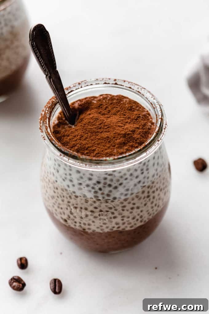 Decadent Tiramisu Chia Pudding 9 A beautifully layered Tiramisu Chia Pudding in a glass cup with a spoon, showing all three distinct layers.