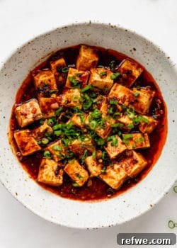 A bowl of delicious Vegetarian Mapo Tofu, garnished with fresh green onions, ready to be served.