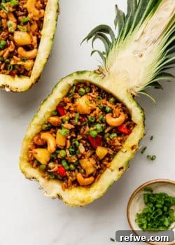 Thai pineapple fried rice in a pineapple bowl with green onions on top