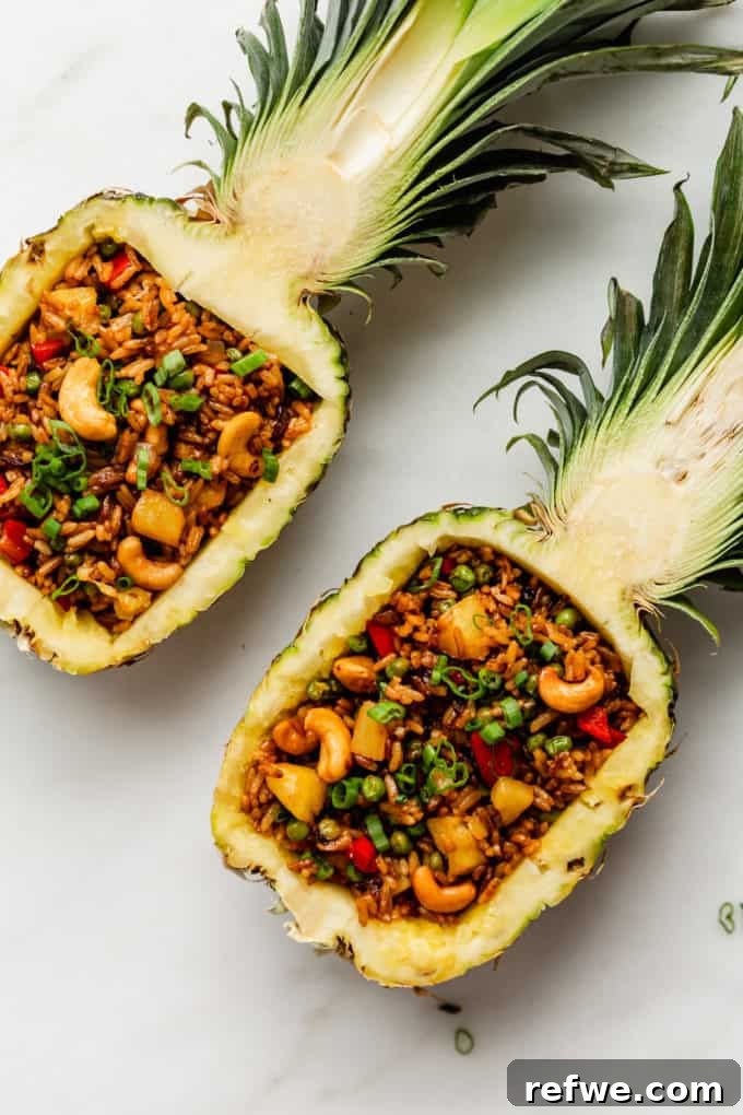 Pineapple Paradise Fried Rice 3 Two halves of a fresh pineapple, expertly hollowed out and ready to be filled with delicious fried rice, on a rustic wooden surface.