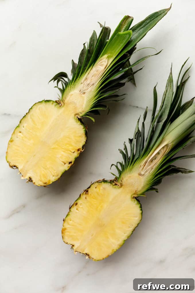 Pineapple Paradise Fried Rice 4 A pineapple precisely cut in half lengthwise, showcasing the initial preparation for creating a pineapple bowl.