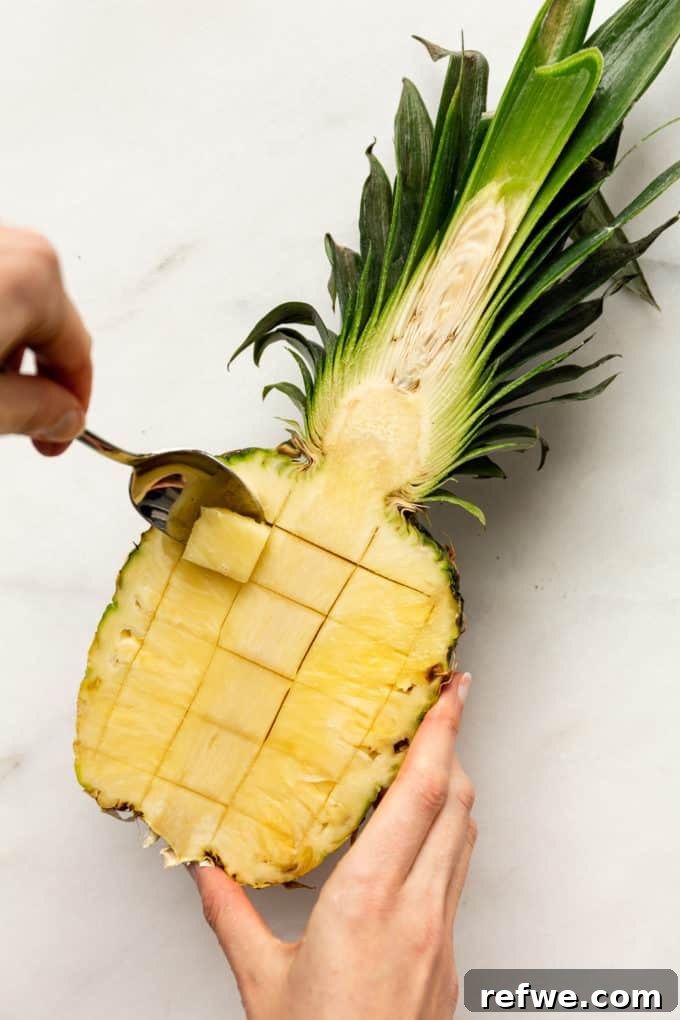 Pineapple Paradise Fried Rice 7 A spoon expertly scooping out chunks of pineapple fruit from its skin, creating a hollow cavity.