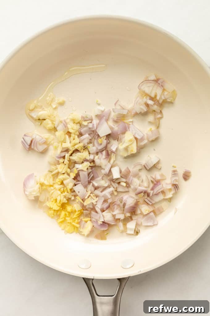 Pineapple Paradise Fried Rice 10 Finely chopped onion, garlic, and ginger sizzling in vegetable oil in a white pan, releasing their fragrant aromas.