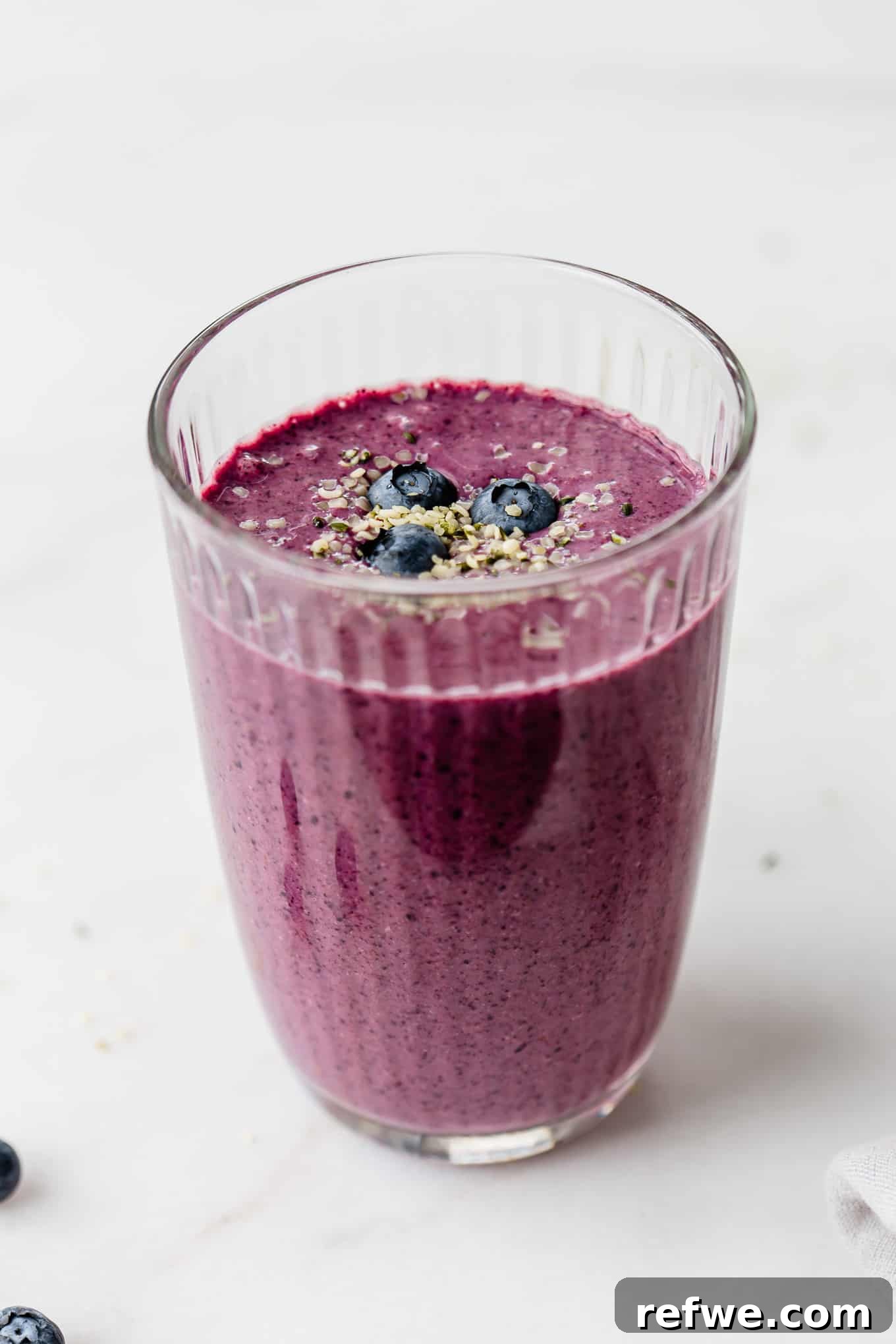 Vibrant Berry Spinach Blend 7 A vibrant blueberry spinach smoothie in a tall glass, garnished with a few fresh blueberries.