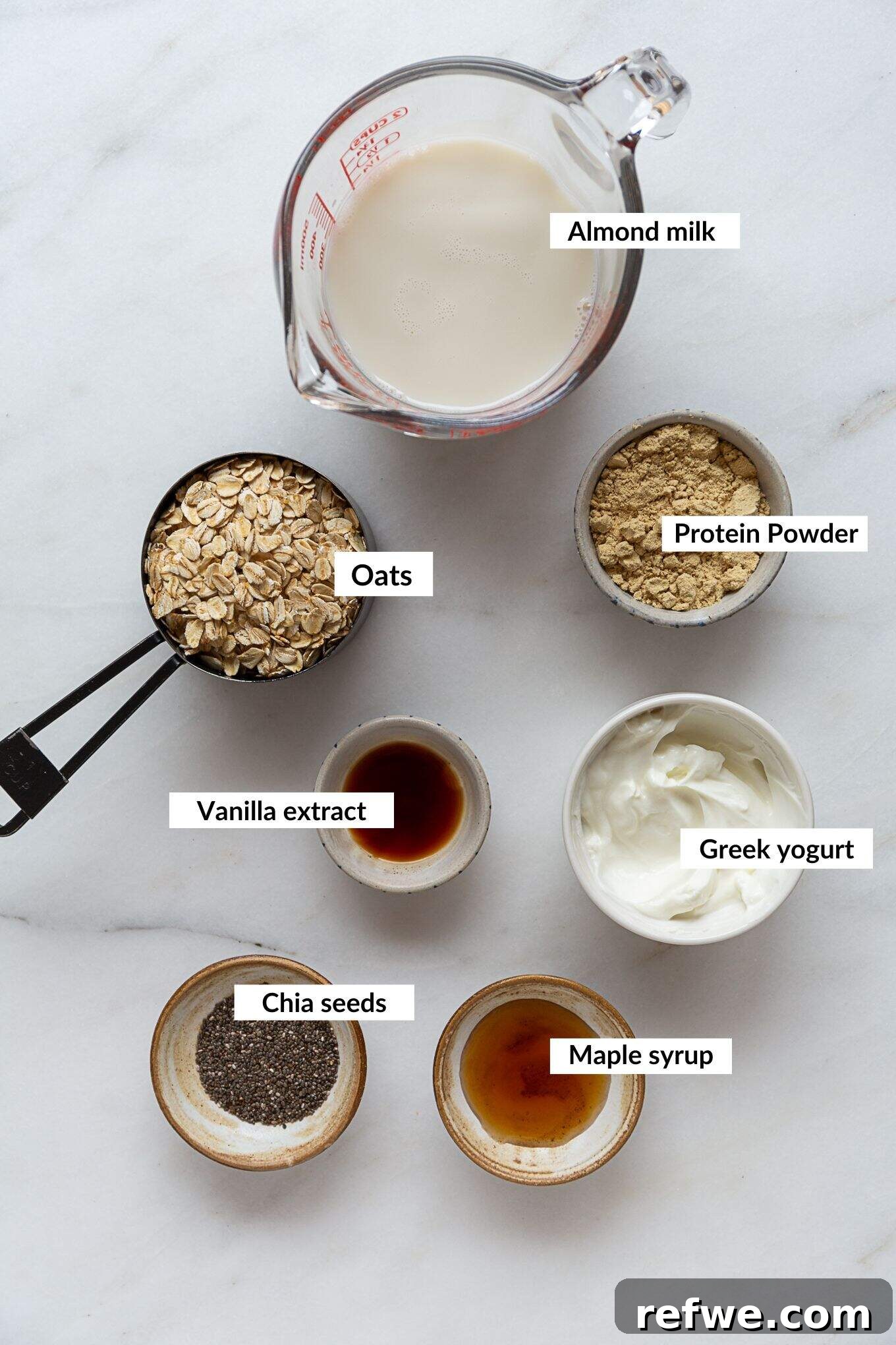 Power Protein Overnight Oats 3 Ingredients laid out to make protein overnight oats: oats, chia seeds, protein powder, milk, yogurt, vanilla extract, and sweetener.