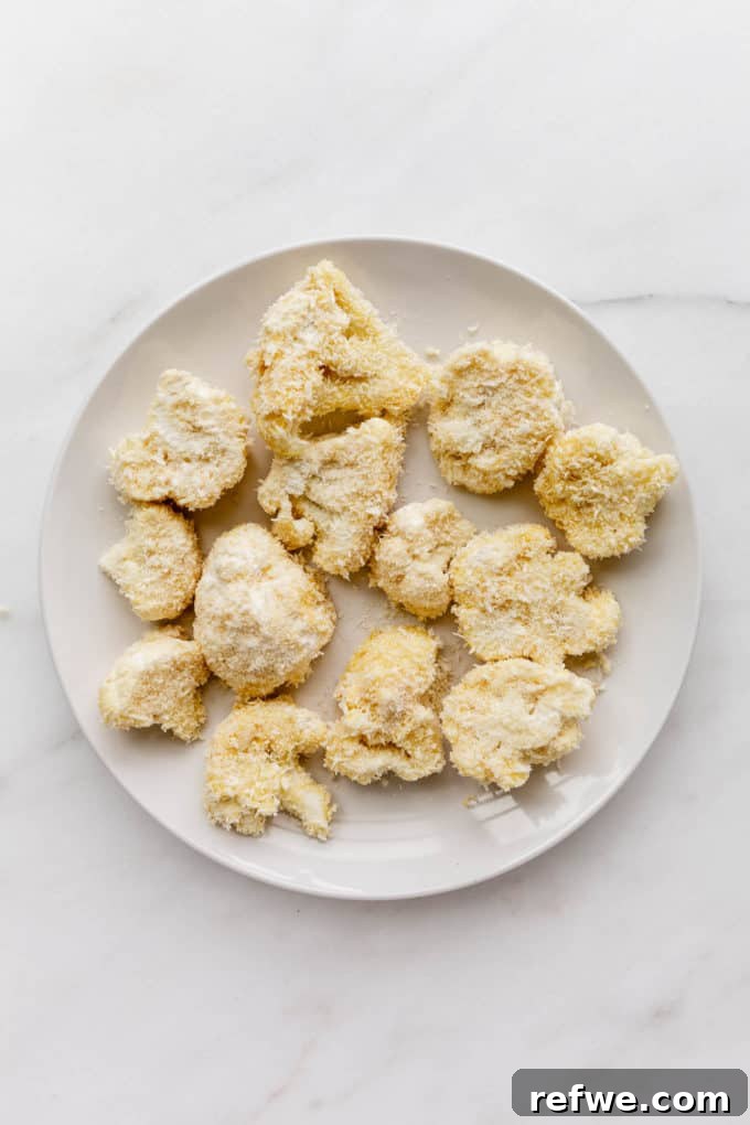 Golden Cauliflower Parmesan Bake 3 Fresh cauliflower florets ready for breading on a white plate