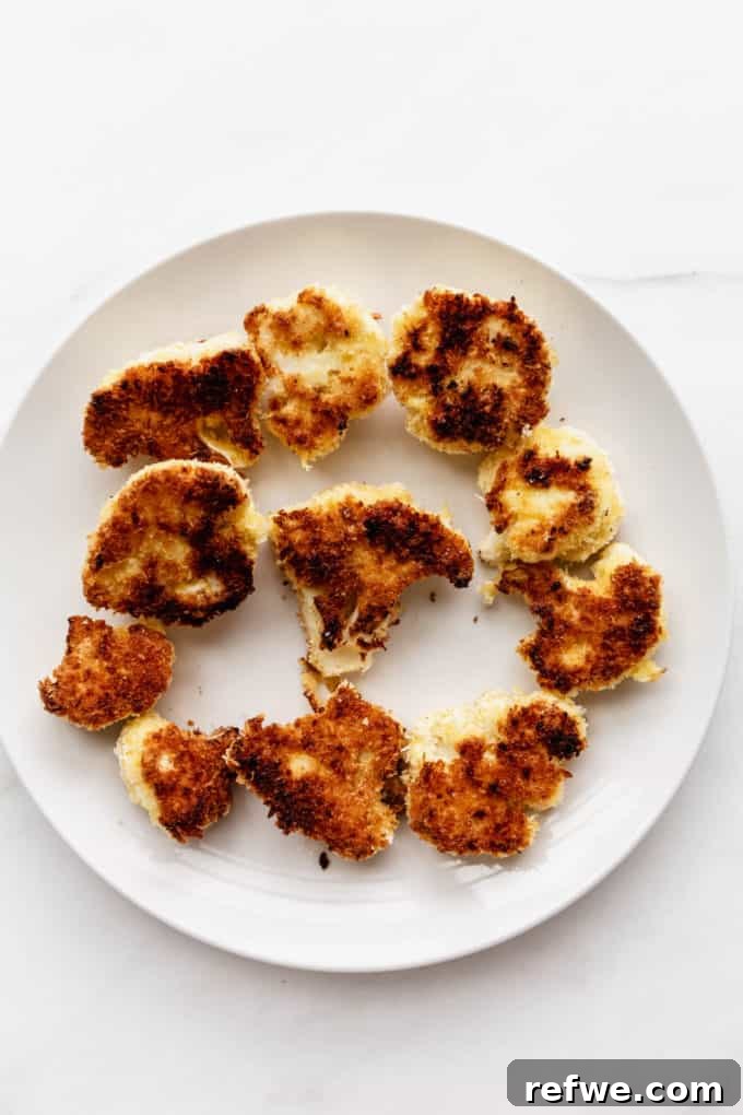 Golden Cauliflower Parmesan Bake 4 Panko-crusted cauliflower florets on a white plate, ready for frying