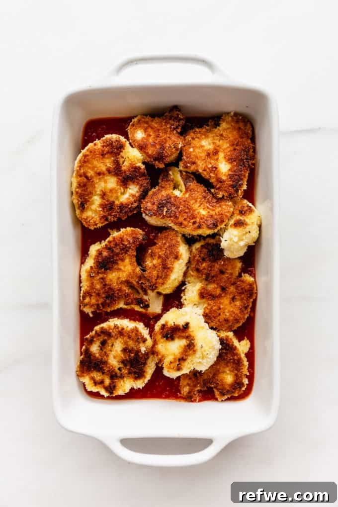 Golden Cauliflower Parmesan Bake 5 Panko-crusted cauliflower arranged in a white baking dish over marinara sauce