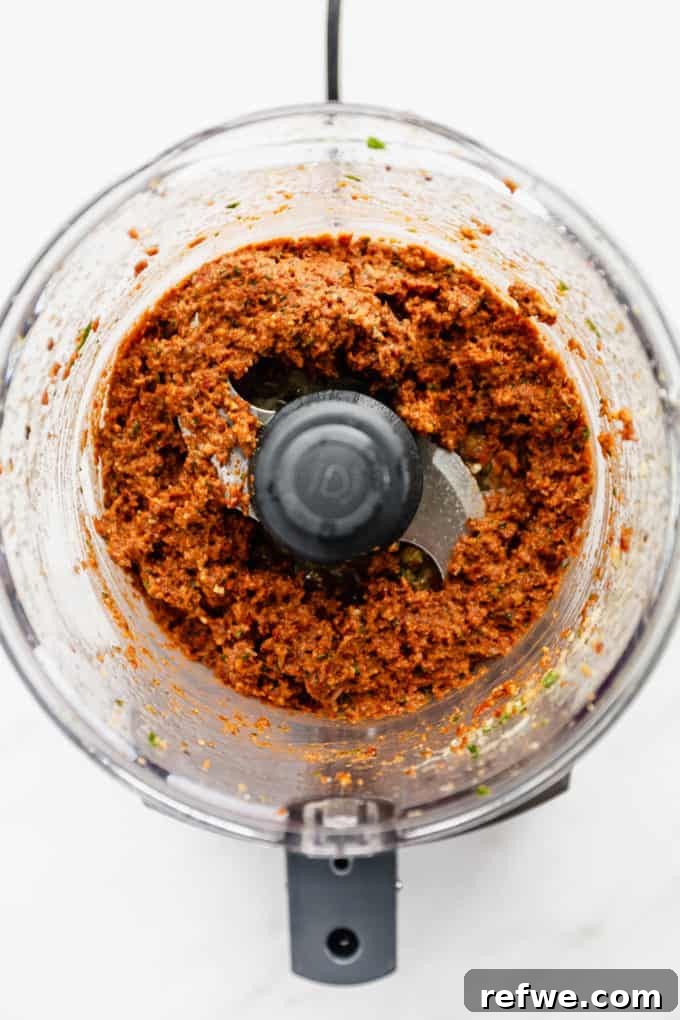 Velvety Red Pesto Pasta 4 The sun-dried tomato pesto in a food processor, after being blended into a smooth, rich paste, showcasing its appetizing texture and deep color.
