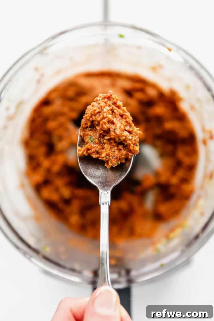 Velvety Red Pesto Pasta 6 A spoonful of vibrant sun-dried tomato pesto, showcasing its rich texture and appetizing color, ready to be mixed with pasta.