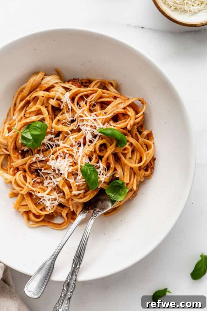 Velvety Red Pesto Pasta 9 A final close-up shot of a generous bowl of creamy red pesto pasta, beautifully garnished with grated Parmesan cheese and fresh basil leaves.